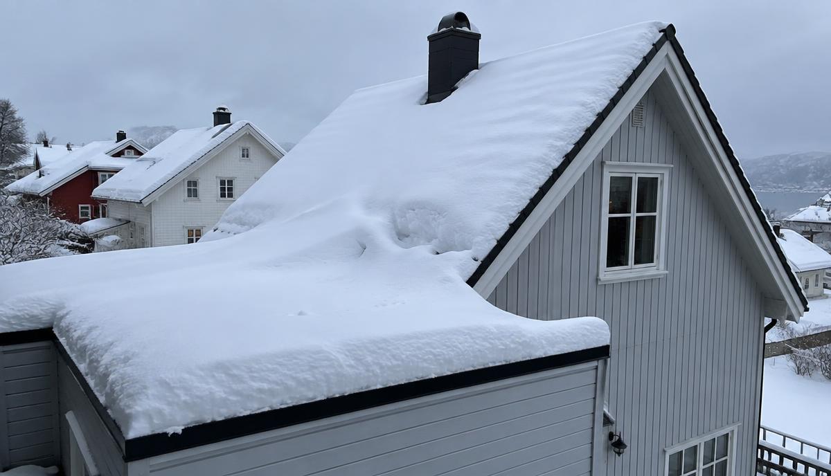 Snødekkete takflater med ujevn snøfordeling og snø som har samlet seg der to taknivåer møtes