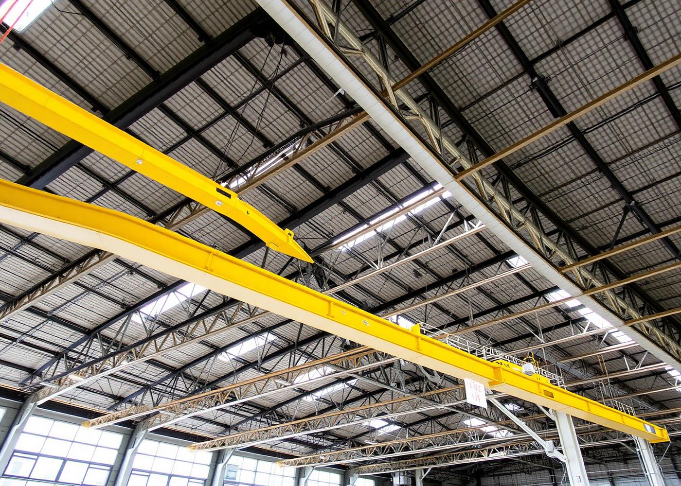 Interior view of a large industrial warehouse with exposed steel roof trusses monitored for structural tilt by NevoSens inclinometer sensors