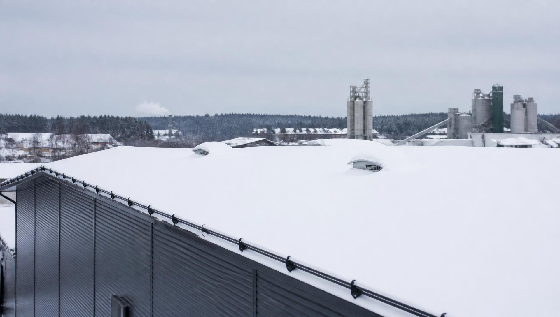 Paksun lumikerroksen peittämä suuren hallirakennuksen peltikatto talvella Suomessa