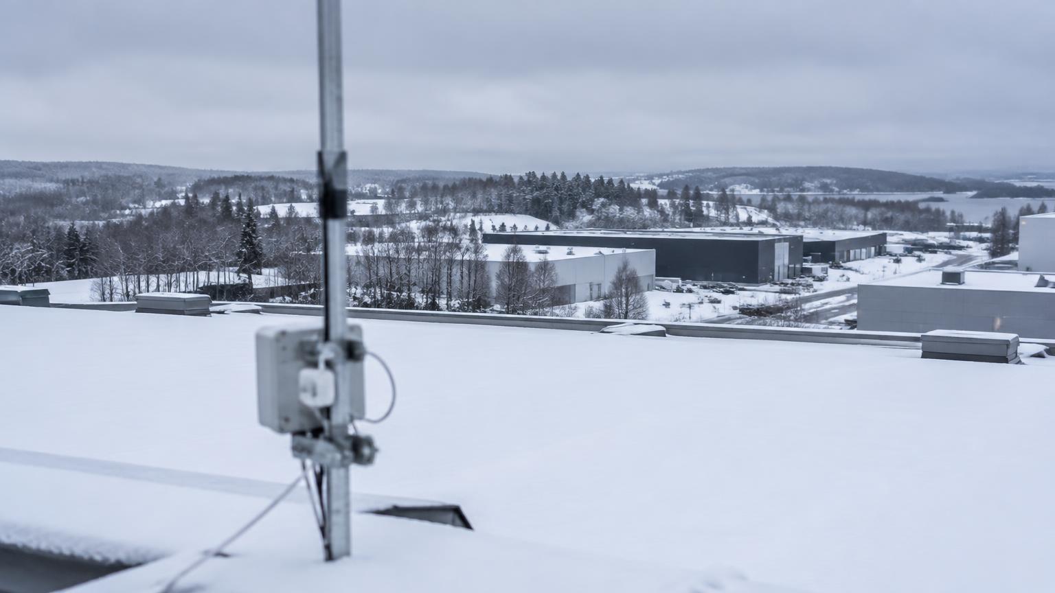 Schneebedecktes Industriedach mit Antennenmast, von dem aus ein LoRa Gateway Sensoren über große Entfernungen erreicht