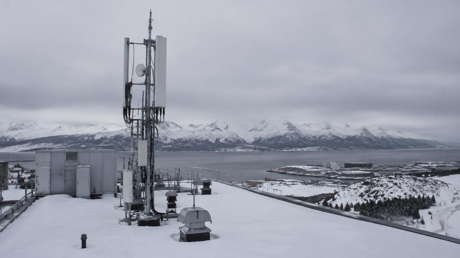 A snowy industrial rooftop with an antenna mast from which a LoRa gateway reaches sensors over long distances